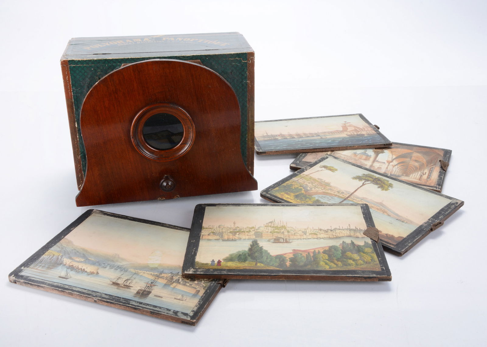 A mid 19th century Polyorama Panoptique optical viewer,: A mid 19th century Polyorama Panoptique optical viewer, the wooden box covered in green and black paper wit label, the viewing front of mahogany with focusing bellows, six hand-coloured paper slides w