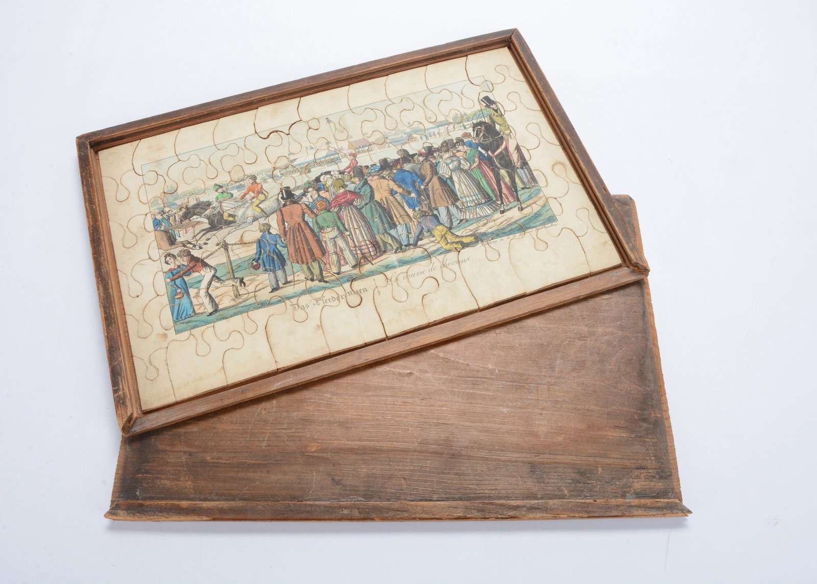 An 1830s G. N. Remmens of Nuremberg dissected puzzle of The Racecourse,: An 1830s G. N. Remmens of Nuremberg dissected puzzle of The Racecourse, hand-coloured print laid on wood, with printer’s details and title in German and French, in plain wooden box with sliding 