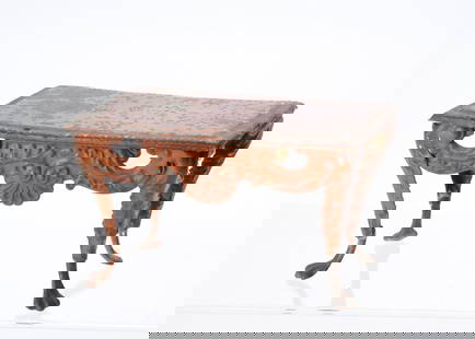 An 19th century Evans & Cartwright tinplate dolls’ house console table,: An 19th century Evans & Cartwright tinplate dolls’ house console table, reddish brown wood grained finish, embossed leaf and shell swags, lion claw feet —5in. (12.5cm.) wide (wear and