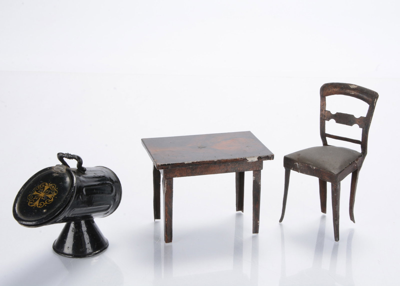 19th century tinplate dolls’ house items,: 19th century tinplate dolls’ house items, a wood grained rectangular table —3 ½in. (9cm.) wide (slight chipping), a similar chair (worn and part repainted) and a black painted coal sc