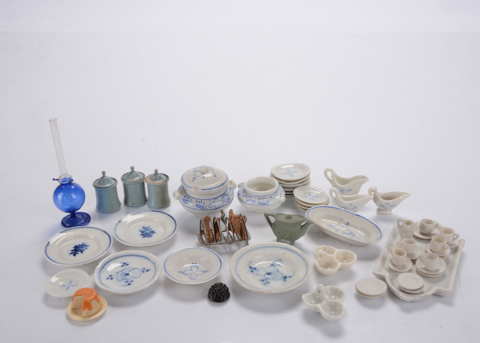 Dolls’ house dinning,: Dolls’ house dinning, part onion flower pattern dinner service, a bisque tea set on tray, a German soft metal toast rack with toast, three turned and painted wooden kitchen canisters, a glass je