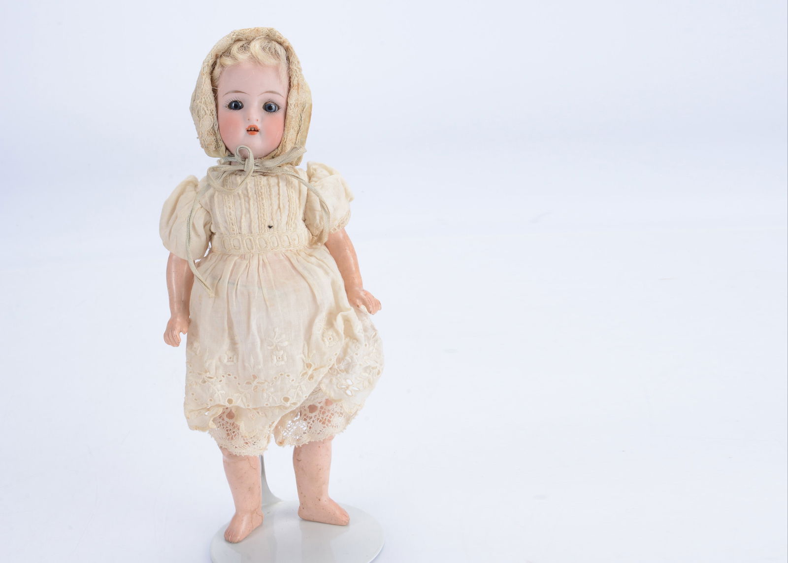 A Simon & Halbig for Kammer & Reinhardt bisque head doll,: A Simon & Halbig for Kammer & Reinhardt bisque head doll, with blue glass sleeping eyes, blond mohair wig, on a jointed composition body with straight arms, wearing a cream cotton dress with pintucked