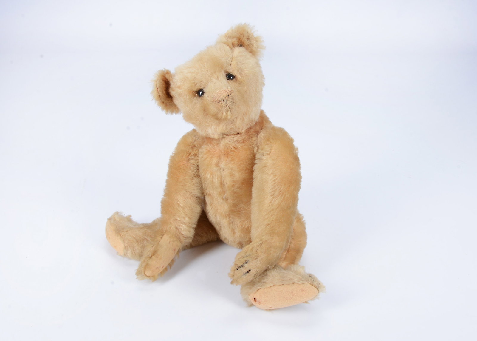 An early small Steiff teddy bear, circa 1906,: An early small Steiff teddy bear, circa 1906, with light golden mohair, black boot button eyes, pronounced muzzle, black stitched four claws, swivel head and jointed elongated limbs with felt pads, hu