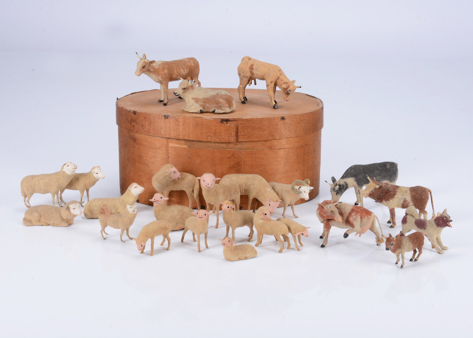 A set of 19th century German composition farm animals with cast-metal legs,: A set of 19th century German composition farm animals with cast-metal legs, flock covered, a barking hound —2 3/4in. (7cm.) long, a Spitz, seven cows including one scratching, ten pink faced she