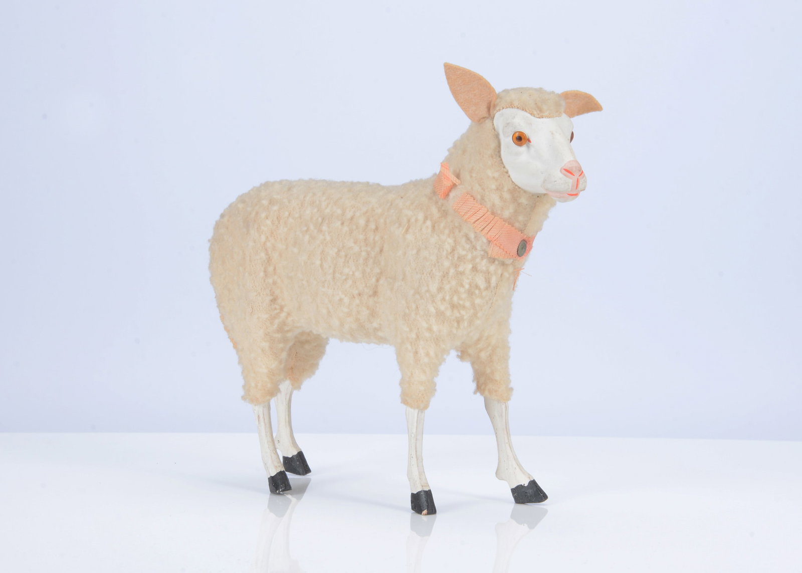 A German composition and wood sheep candy container, circa 1910,: A German composition and wood sheep candy container, circa 1910, with wool plush covering, glass eyes, pink ribbon and removable head to reveal secret compartment —8in. (20cm.) long