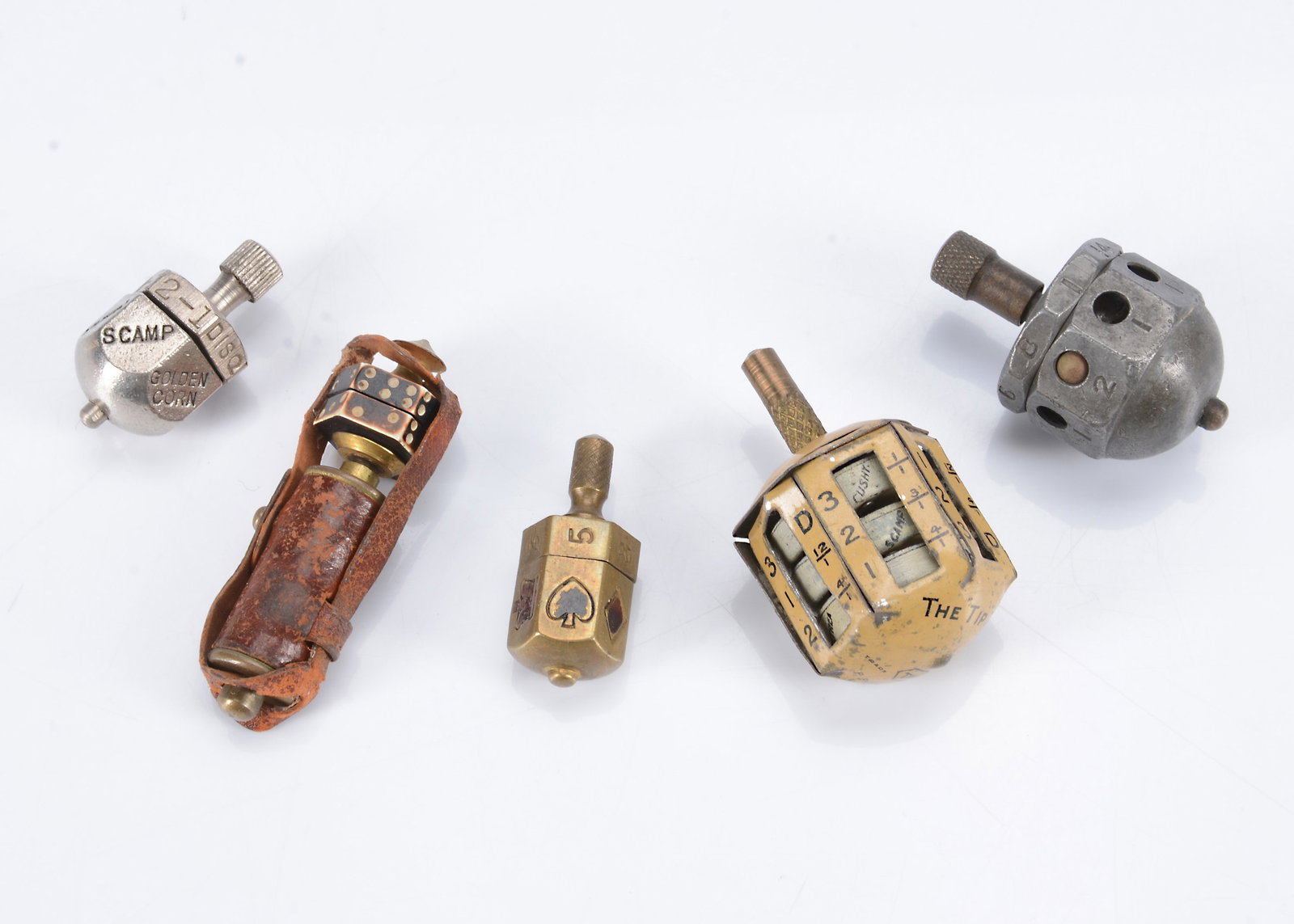 Five post-war metal teetotums,: Five post-war metal teetotums, an unusual example in a leather case, brass with bone hexagonal die, possibly some sort of trigger mechanism —2in. (5cm.) high, a tinplate ‘The Tip Top’