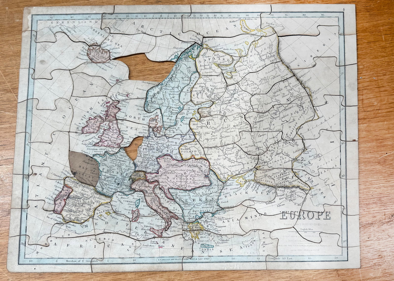 A mid 19th century G. F. Cruchley ‘Europe’ dissected puzzle,: A mid 19th century G. F. Cruchley ‘Europe’ dissected puzzle, hand coloured and printed paper laid down on wood, guide, in unmarked green paper covered card box—18 1/2in. (47cm.) wide