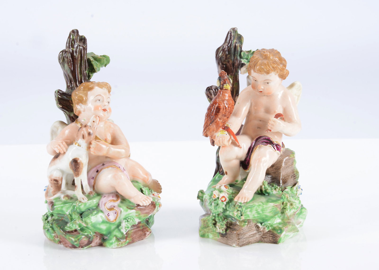 A pair of Derby porcelain seated cherubs from a series of senses, circa 1780,: A pair of Derby porcelain seated cherubs from a series of senses, circa 1780, sight represented by a cherub sat on a rock with hooded bird of pray —4 1/4in. (11.5cm.) high (restored wing and bro