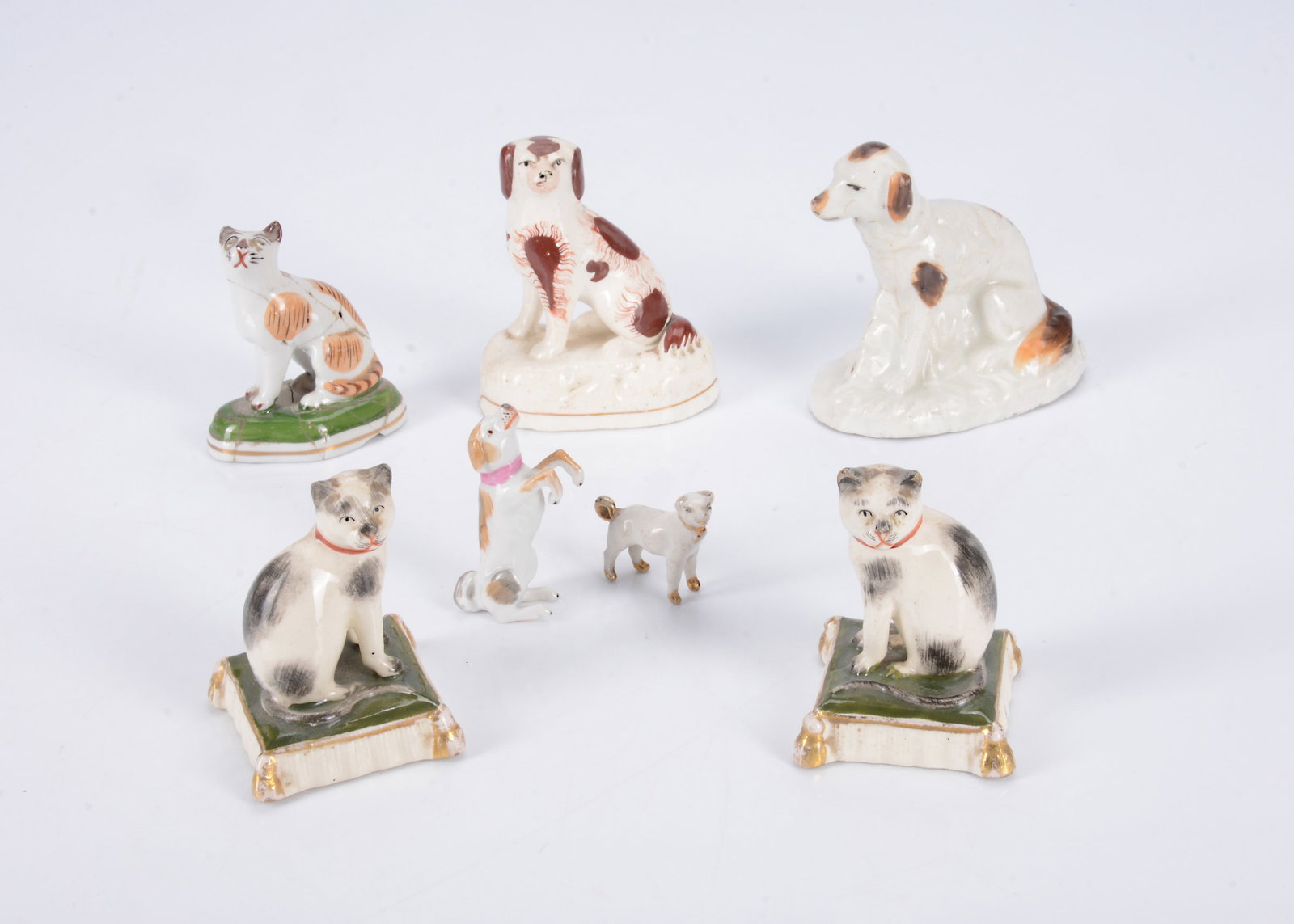 Dogs and cats,: Dogs and cats, a Staffordshire spaniel, circa 1850 —3 1/4in. (8cm.) high, a German porcelain begging dog, a Samson cat (broken and glued) and other items