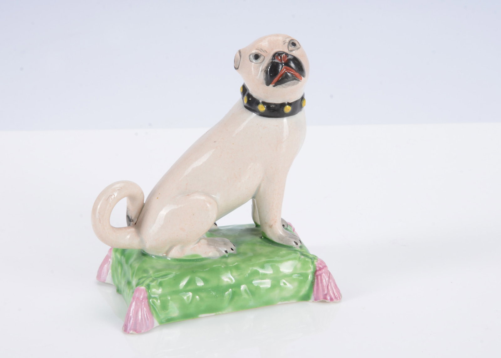 An English pearlware pug dog seated on a cushion, circa 1820, (1 of 2)
