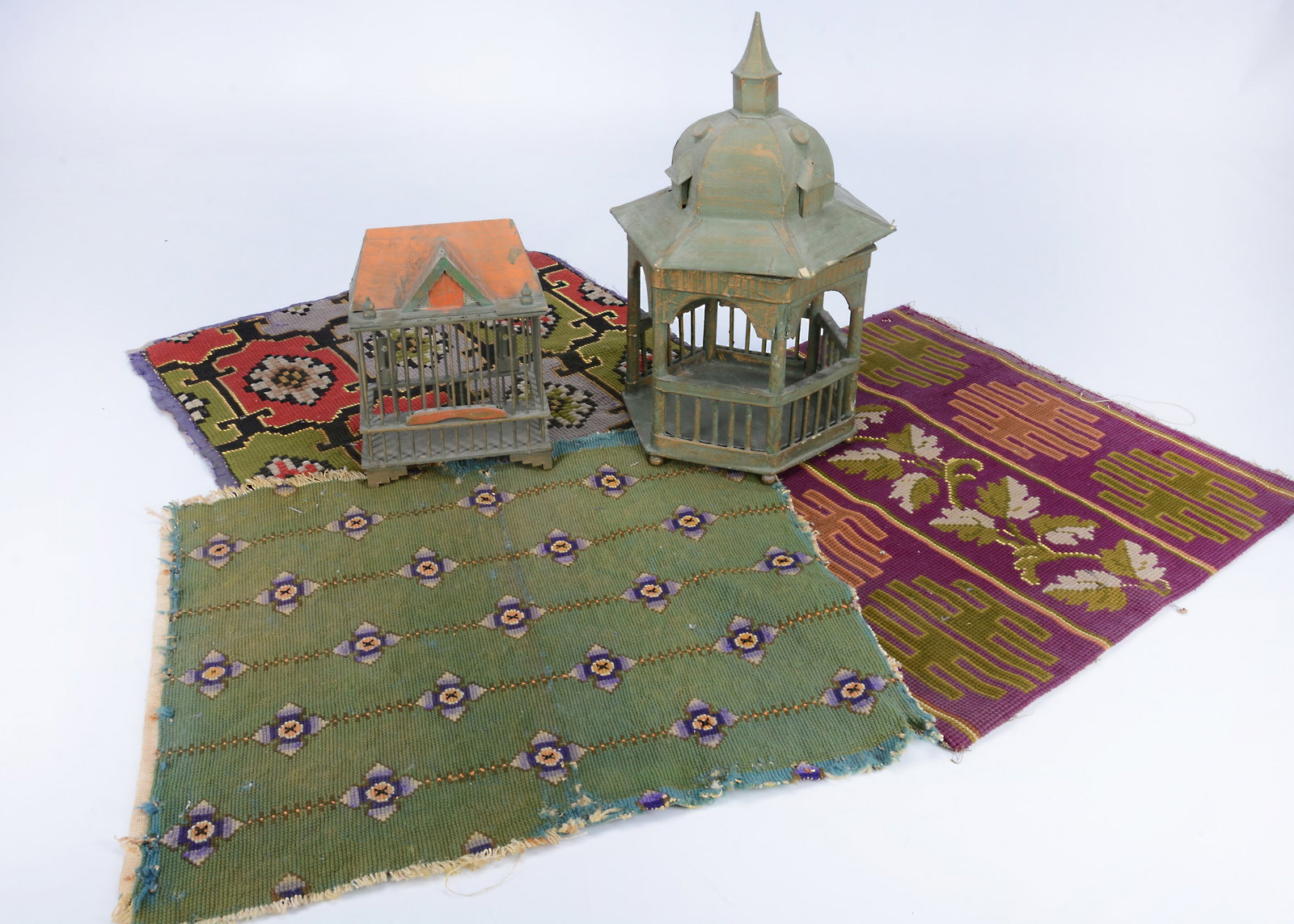 Three 19th century wool work squares,: Three 19th century wool work squares, used as doll display carpets, but could be made into cushion covers —19in. (48cm.) square (slight damage); a papier-mâché garden pavilion and bird