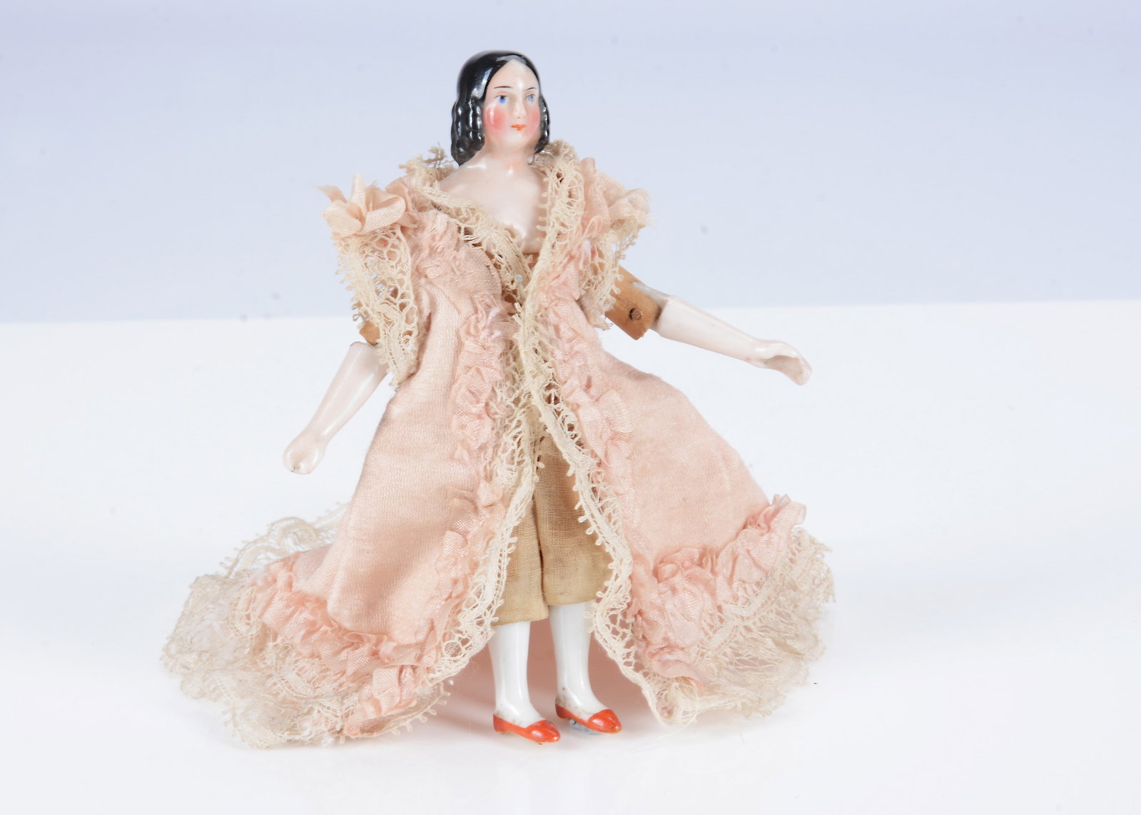 A rare Kister china shoulder-head dolls’ house doll.: A rare Kister china shoulder-head dolls’ house doll. pink tinted with blue painted eyes, black painted and moulded centre-parted hair falling in ringlets, wooden jointed body, pink tinted forear