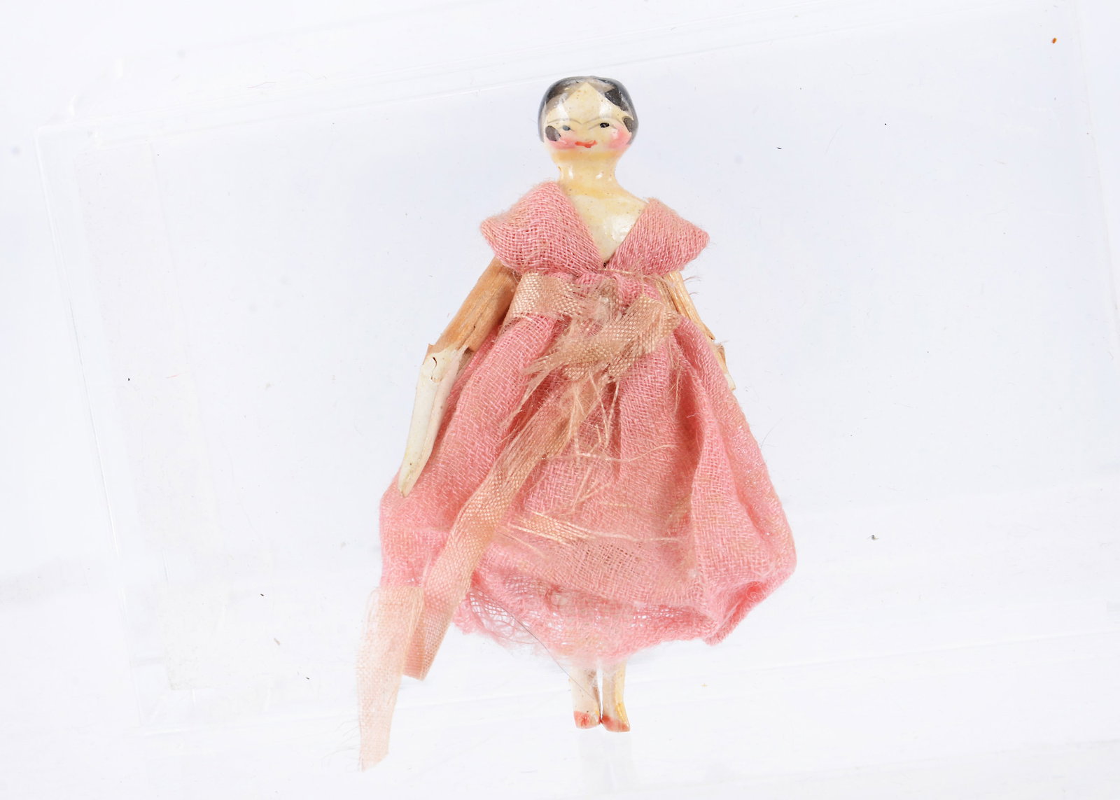 An 19th century Grodnertal carved wooden small dolls’ house doll,: An 19th century Grodnertal carved wooden small dolls’ house doll, painted head and shoulders, black eyes, black painted hair with centre parted fringe, wooden body joints at shoulders, elbows, h