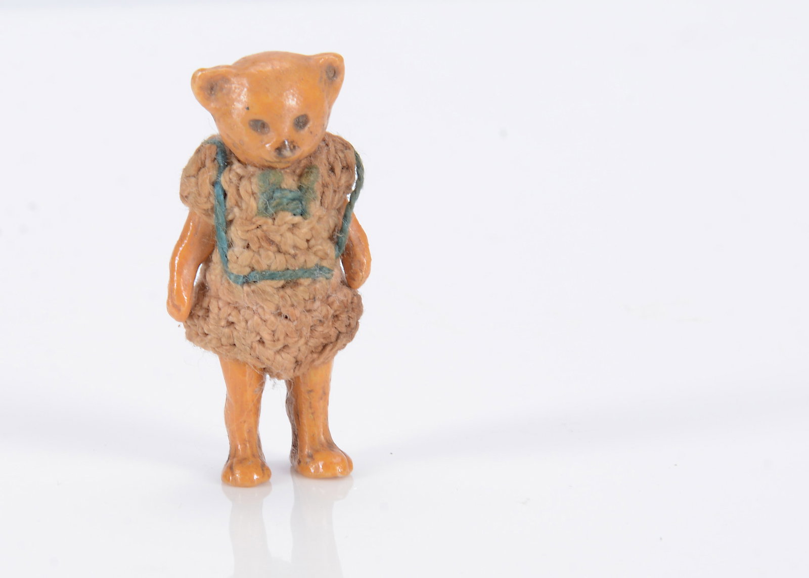A Hertwig all-bisque teddy bear dolls’ house doll,: A Hertwig all-bisque teddy bear dolls’ house doll, painted golden brown, pin jointed limbs and original crochet outfit —1 1/2in. (4cm.) high