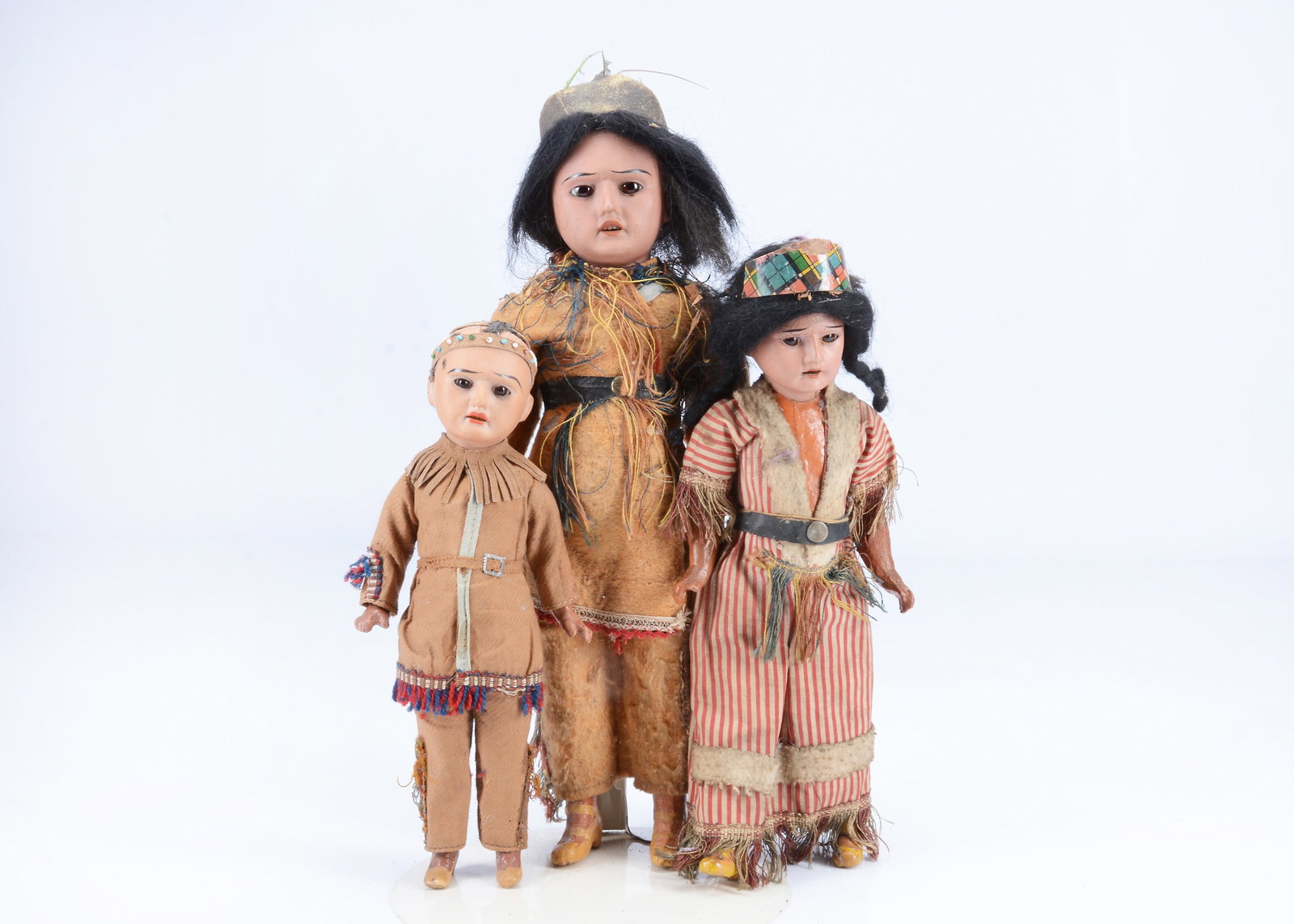 Three Armand Marseille Native American dolls,: Three Armand Marseille Native American dolls, with brown bisque heads, strong brows, fixed brown glass eyes, two with black mohair wigs, straight limbed composition bodies and original costumes —