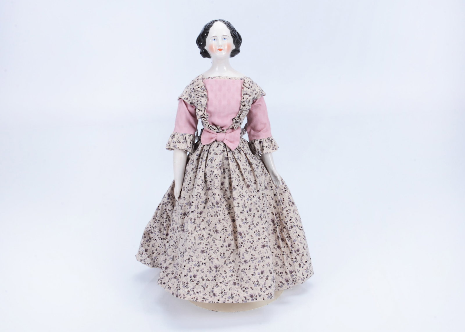 An 19th century German slight pink tinted china shoulder head doll with elaborate hair style,: An 19th century German slight pink tinted china shoulder head doll with elaborate hair style, with blue painted eyes, red inner eye dot and eyelid line, half exposed ears, centre-parted wavy hair fall