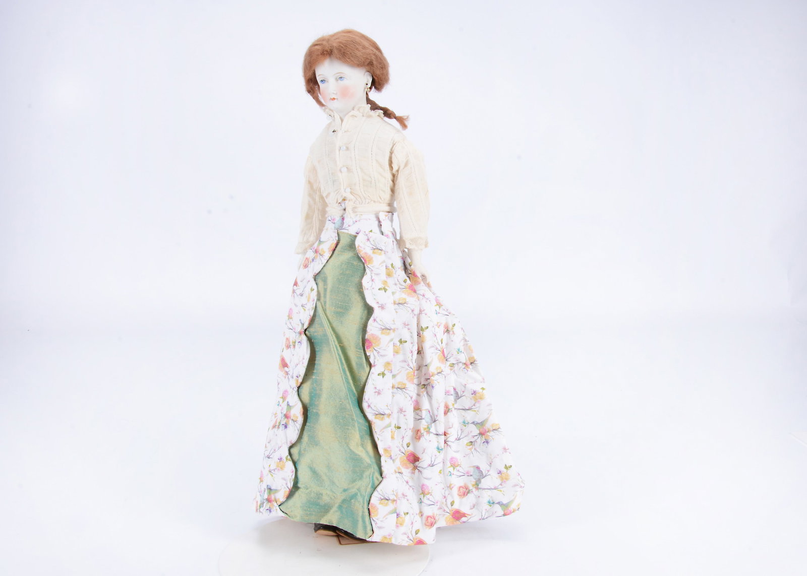 An unusual German solid domed head shoulder-head doll,: An unusual German solid domed head shoulder-head doll, with blue painted upward glancing eyes, red eyelid line, single stroke brown brow, pierced ears, solid domed pate, later wig, stuffed body with b