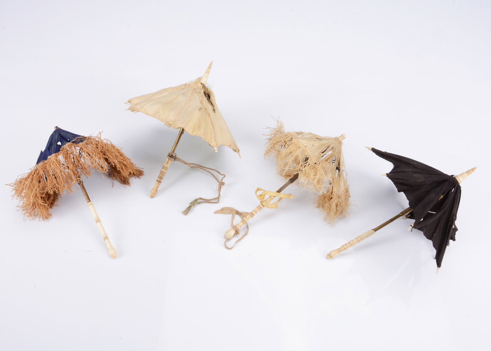 Three fashion doll parasols and an umbrella to restore,: Three fashion doll parasols and an umbrella to restore, all with bone handles, the largest with black silk --7 3/4in.(19.5cm.) long (silk torn) (4)