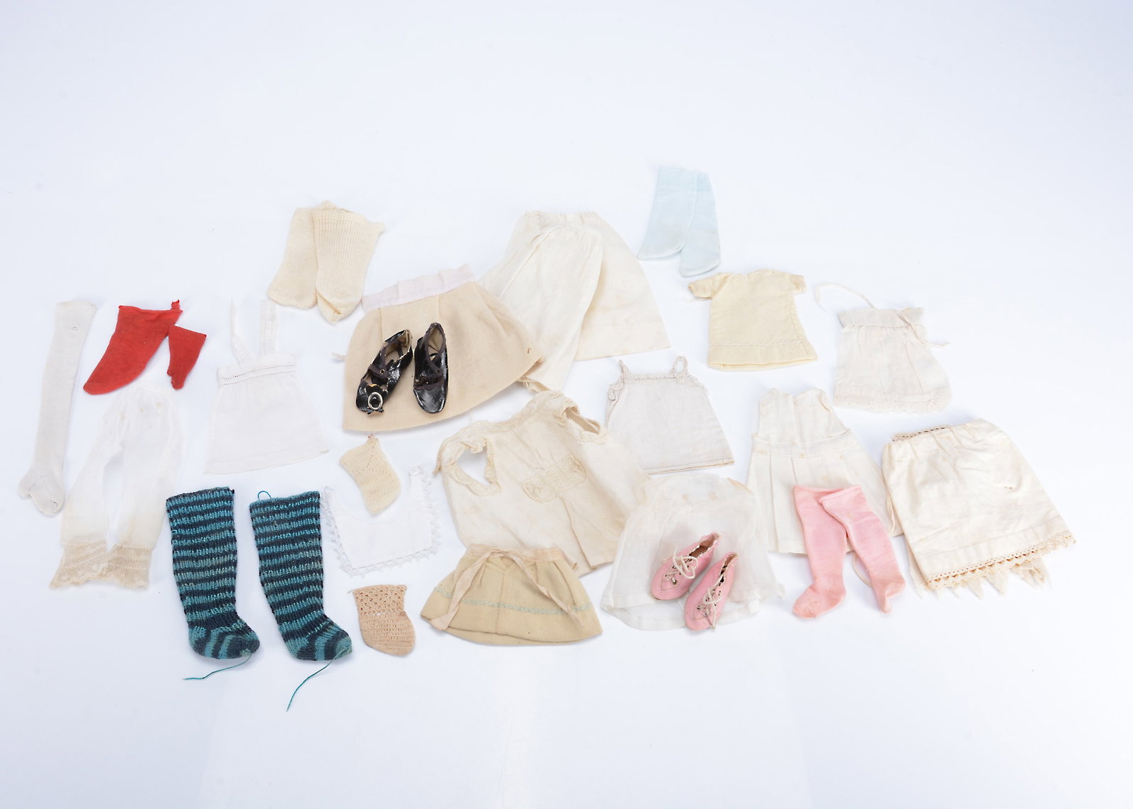 Dolls accessories,: Dolls accessories, a pair of pink silk shoes, stamped 3 to sole, a pair of black oil cloth shoes; four pairs of socks, a small white cotton pinafore--4in. (10cm.) neck to hem; muslin bloomers with lac