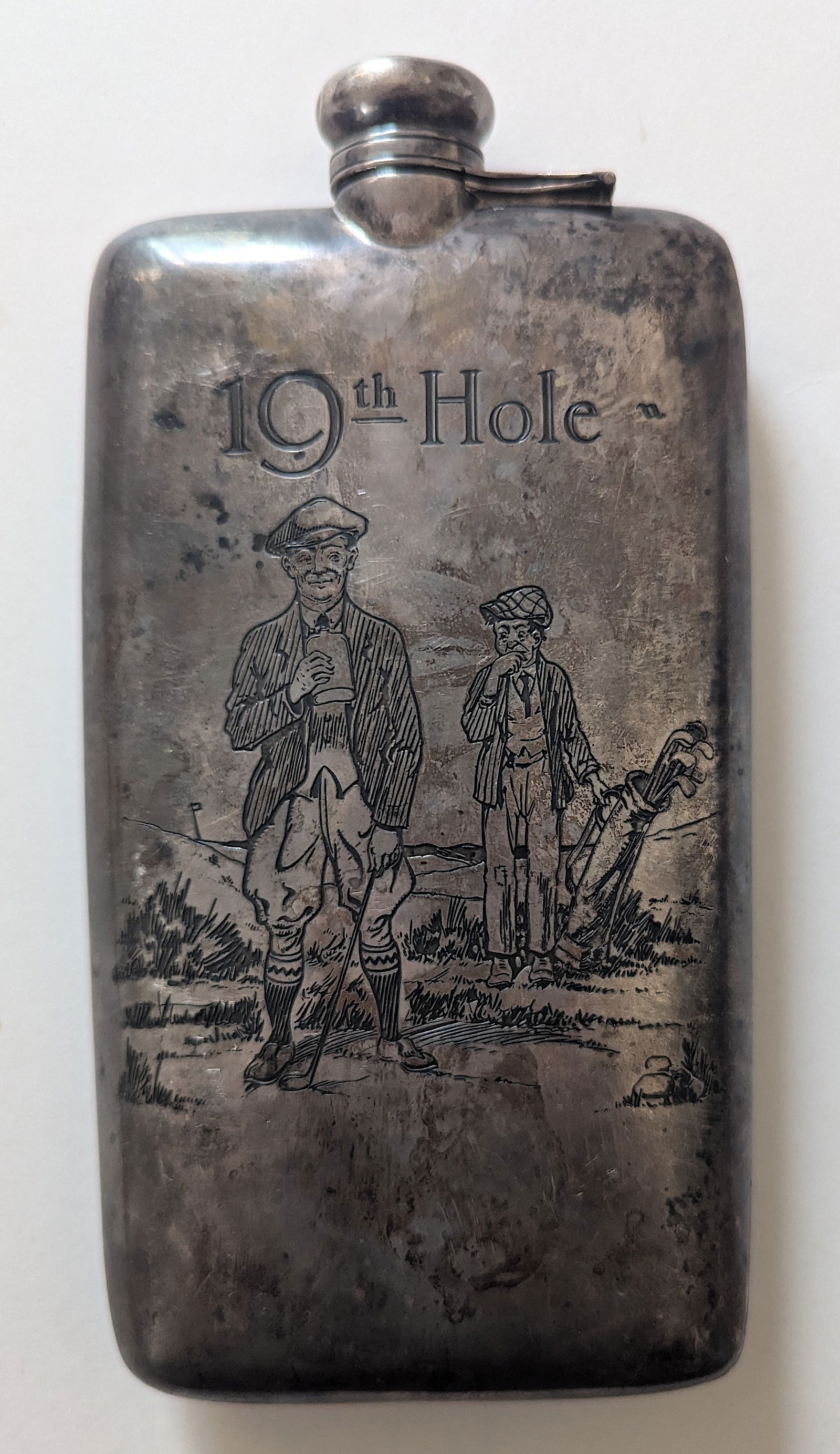 19th Hole Sterling Silver Golfing Flask: Large sterling silver flask with attached screw-top lid (with cork on inside). Marked sterling. Flask to hold 7/8 Pint. 20x9 cm. (8x3½"). With an engraved golfing illustration. Approx. Weight 1