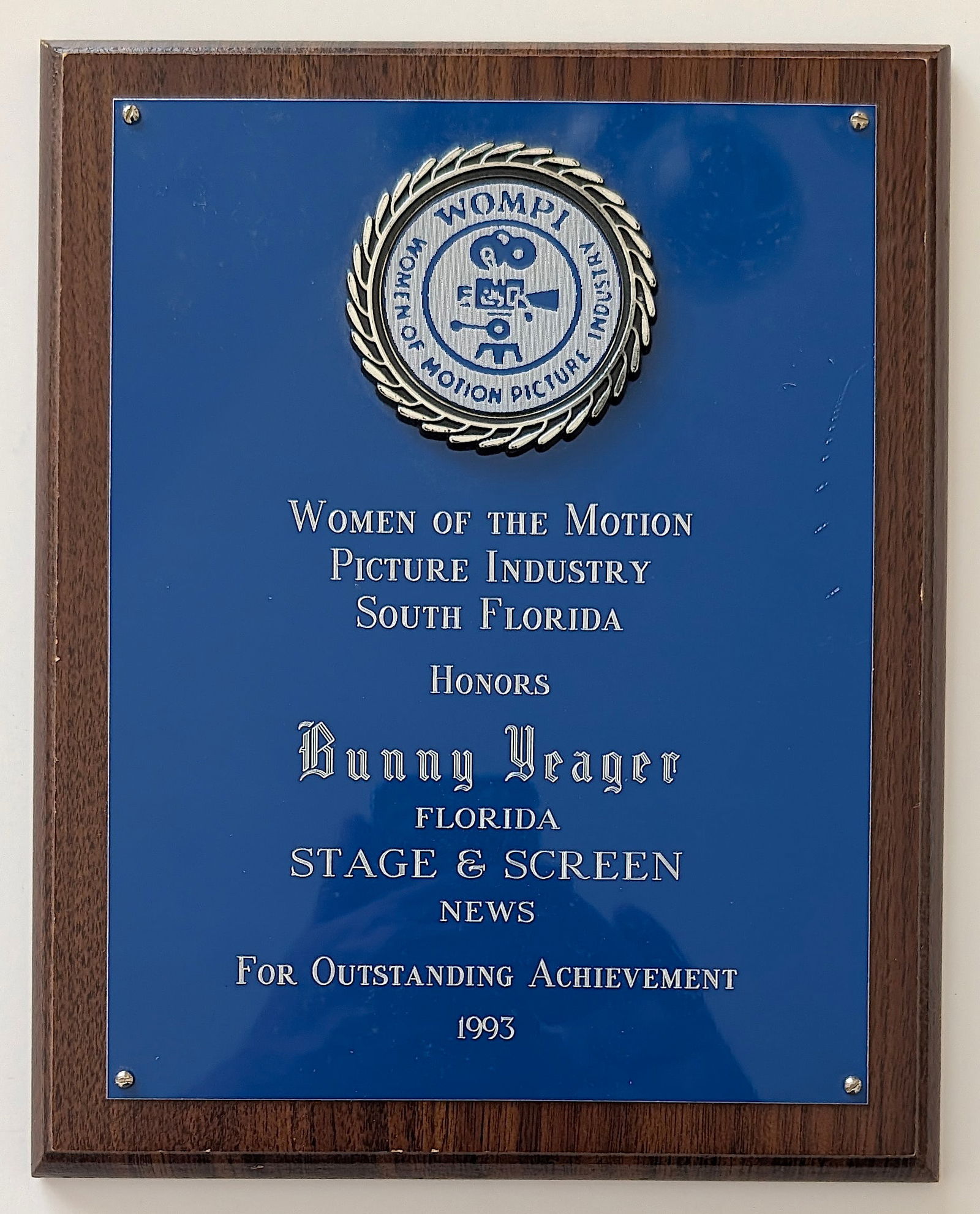 Commemorative Plaque Presented to South Florida icon BUNNY YEAGER: The award is from the Women of the Motion Picture Industry South Florida (WOMPI). It honors Yeager for "Outstanding Achievement" in 1993. Bunny Yeager was a renowned model, photographer, and author be