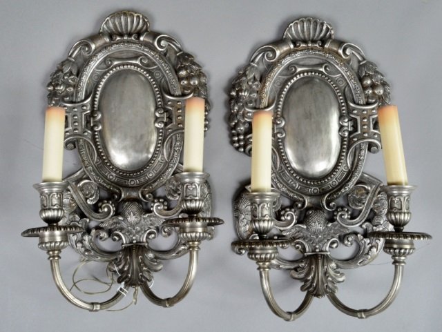 Pair of Nickel Plated Brass Two Arm Sconces: Heavily cast, with shield backs and shell motif. Height 22 inches, width 13 inches.