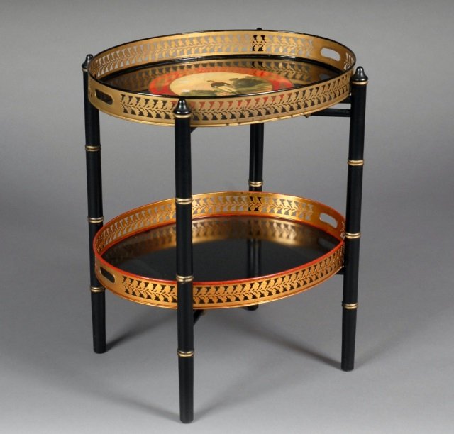 English Regency Style Two Tier Table: Tole oval top with painted decoration and pierced gallery, four ebonized wood turned supports, and a lower conforming tole shelf. Height 27 inches, width 22 inches, depth 18 inches.