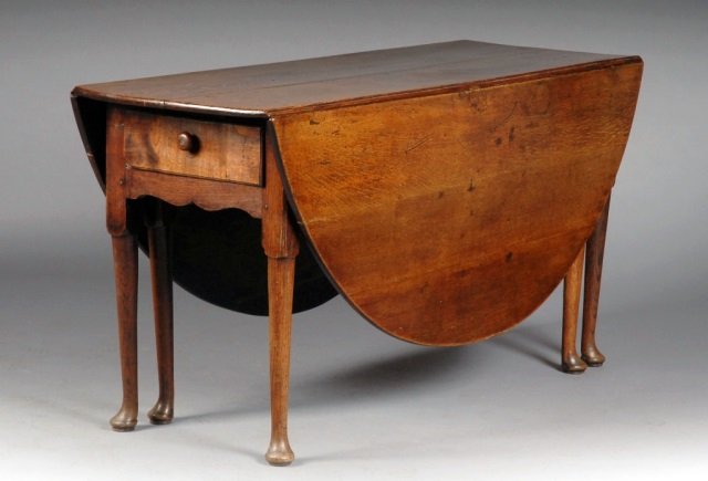 Queen Anne Oak Drop Leaf Table: Mid 18th century. Rectangular top flanked by two D shaped leaves, above a single drawer, round turned legs with Dutch pad feet. Height 30 inches, width 66 inches, depth 58 inches.