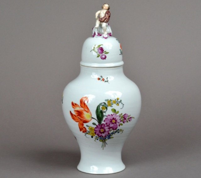 White Meissen Porcelain Ginger Jar: Surmounted by a figure of a putti, with floral decoration. Height 15 1/2 inches, width 8 inches.