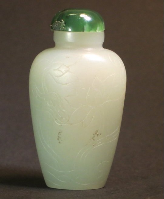 Antique Chinese white jade snuff bottle: Antique Chinese jade snuff bottle, white jade of pale celadon color stone in a tapering form, incised with lotus plants. Dimension: 2 1/8 in. (5,4 cm). Age: Pre 1910. Provenance: Collection of Christe