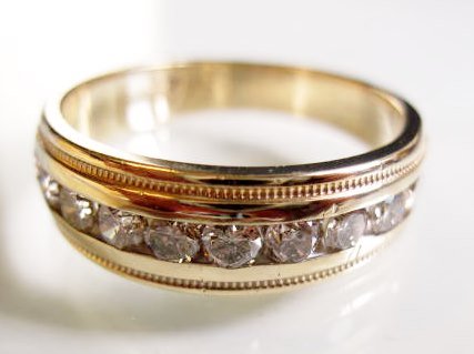 10K Diamond Wedding Band: A 10K yellow gold men's diamond wedding band. The band contains 11 diamonds in the 6-8 point range for a total weight of approximately .75 carats. Band tapers from 7mm wide on top to 5mm. Finger size 