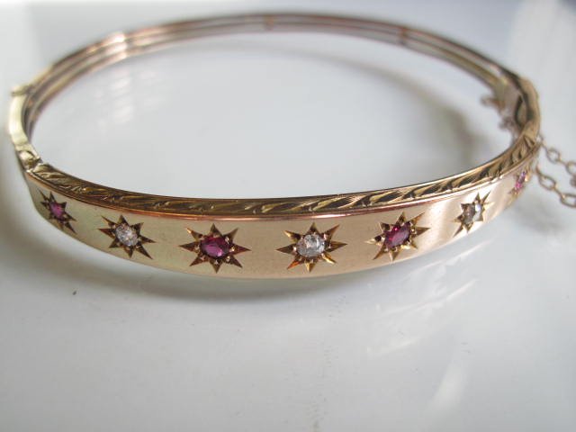 9K Victorian Bangle: A 9K yellow gold hinged Edwardian bangle set with rubies and diamonds. Diameter just shy of 2-1/2 inches. Weight 7.8 grams. Some minor wear commensurate with age.