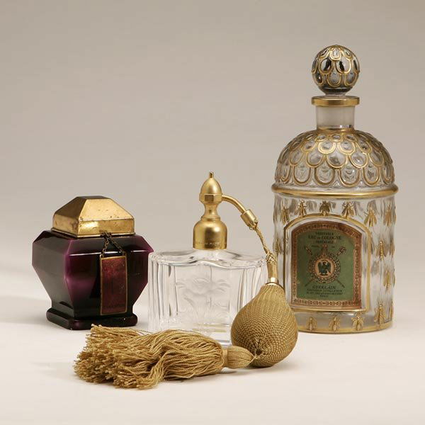 A GROUP OF THREE FRENCH GLASS PERFUME BOTTLES: late 19th/early 20th century; comprising an Art Deco Myon "Exaltation" bottle marked "Myon/Paris-France" and "Baccarat/France", aubergine, with gilt enamelled top and stopper, pendant tag; A Guerlain