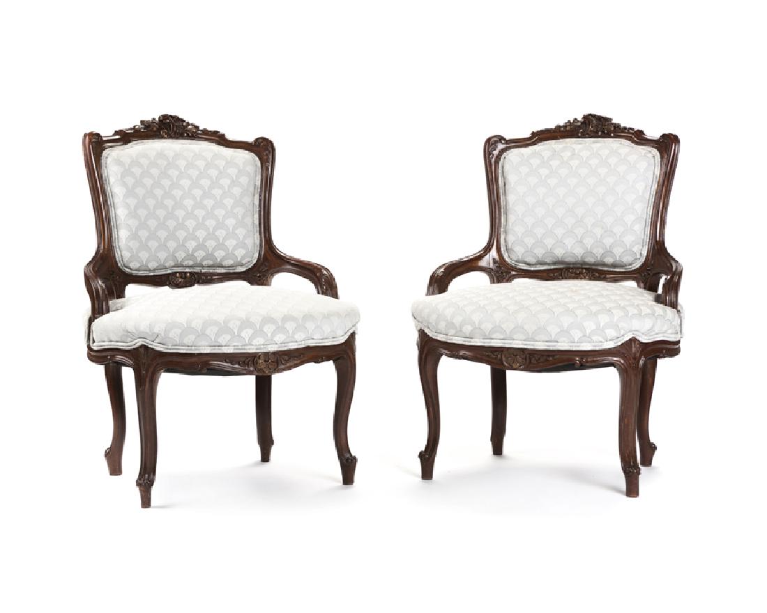 A pair of Louis XV-style carved wood armchairs: Mid-20th century Each carved wood frame surmounted by a rocaille and floral crest, over an oblong seat on cabriole legs, 2 pieces Each: 32" H x 22.75" W x 22" D Provenance: Private Collection, Beverly