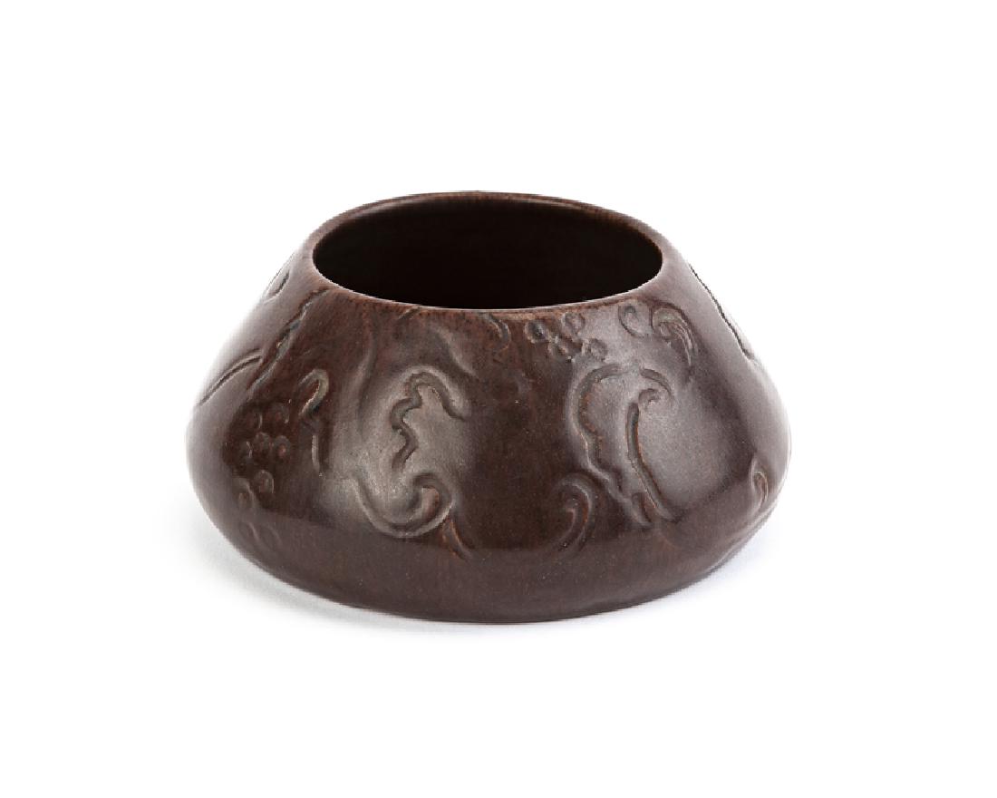 A glazed burgundy pot, Arequipa: Circa 1911-1918, Marin County, CA Stamped to bottom: Arequipa / California / 552 / 10RP Decorated with raised grape vines, burgundy glaze 2.625" H x 5.625" Dia.