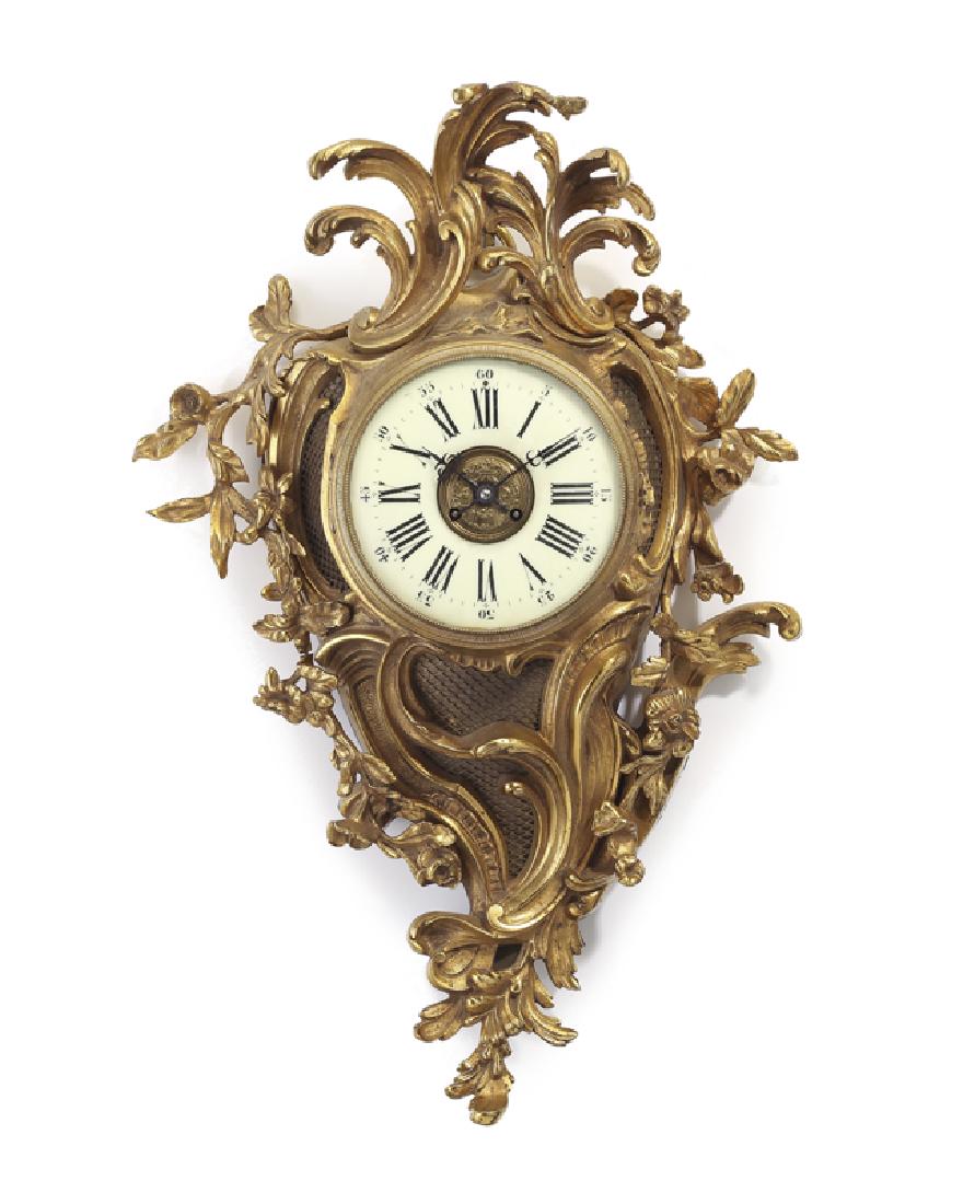 A Louis XV-style gilt-bronze cartel clock: Early 20th century Movement numbered: 674 With high relief rocaille and floral spray case centering a white round dial with Roman numeral hour markers and Arabic secondary track 28.75" H x 20" W x 6.2