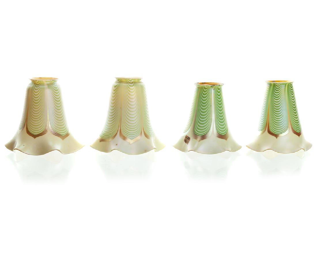 Four art glass shades: Apparently unsigned Each with pulled green feather design on white ground with fluted rim and yellow irisdescent interior, 4 pieces Each: 5.125" H x 5.125" W x 5.125" D Provenance: The Estate of Harry