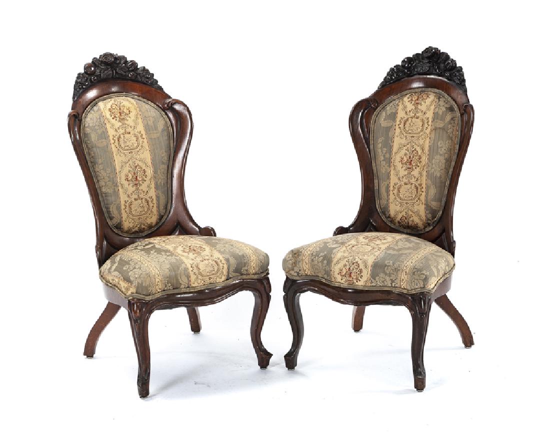 A pair of Victorian carved and laminated wood chairs: Mid-19th century Each topped with a carved swag of roses and gourds over a carved and upholstered back rest issuing a scalloped upholstered seat raised on cabriole legs, 2 pieces Each: 36.5" H x 22.5"