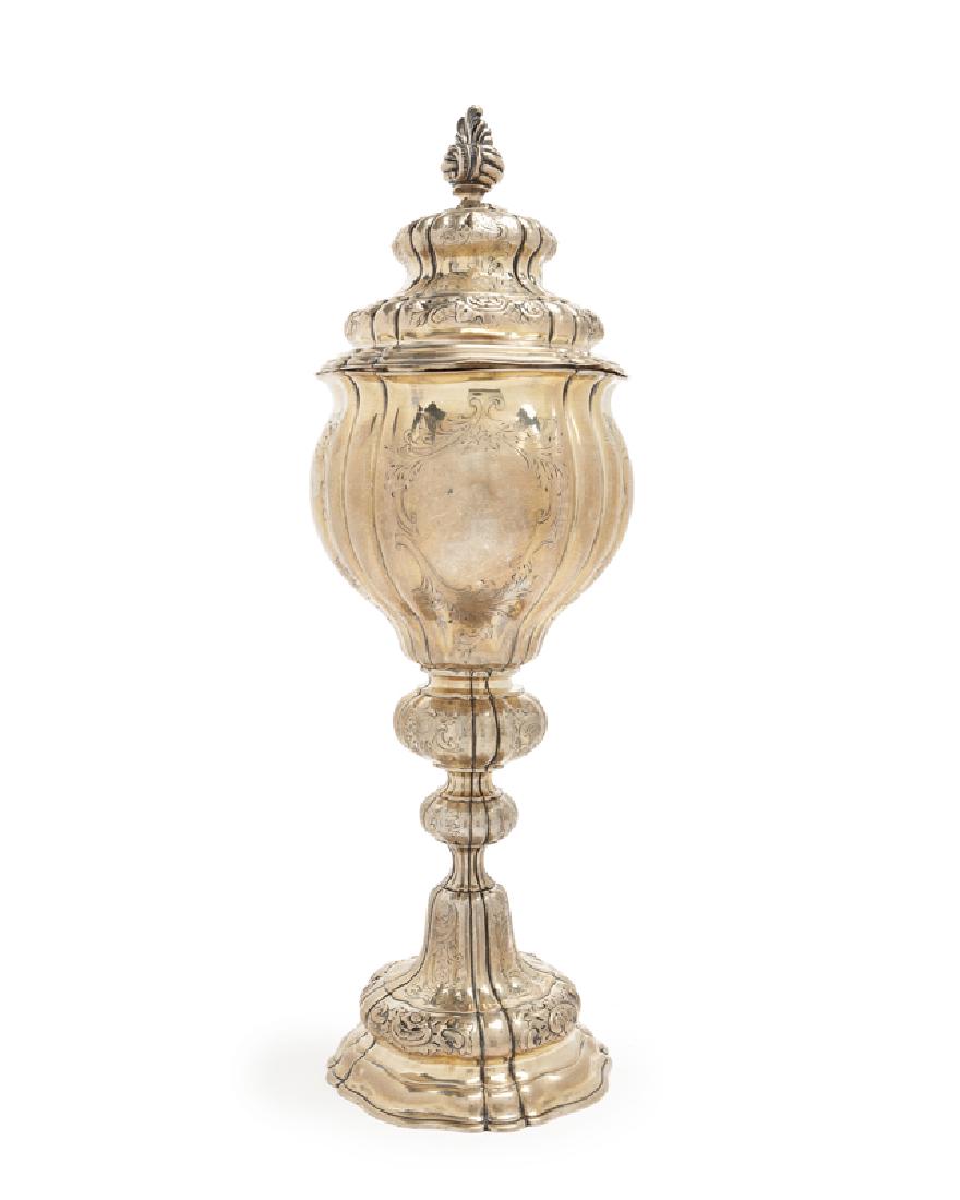 An .800 silver chalise with lid: Mid-19th century Stamped: B [in oval]; E.Frd [in rectangle]; further stamped with indistinct marks The rocaille finial over a repousse and chased lidded chalise raised on a knopped and widening scallo