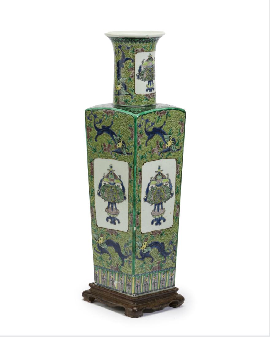 A Chinese green porcelain vase: 20th century The long neck vase over a tapering squared body raised on a wooden plinth Vase: 20" H x 5.5" W x 5.5" D