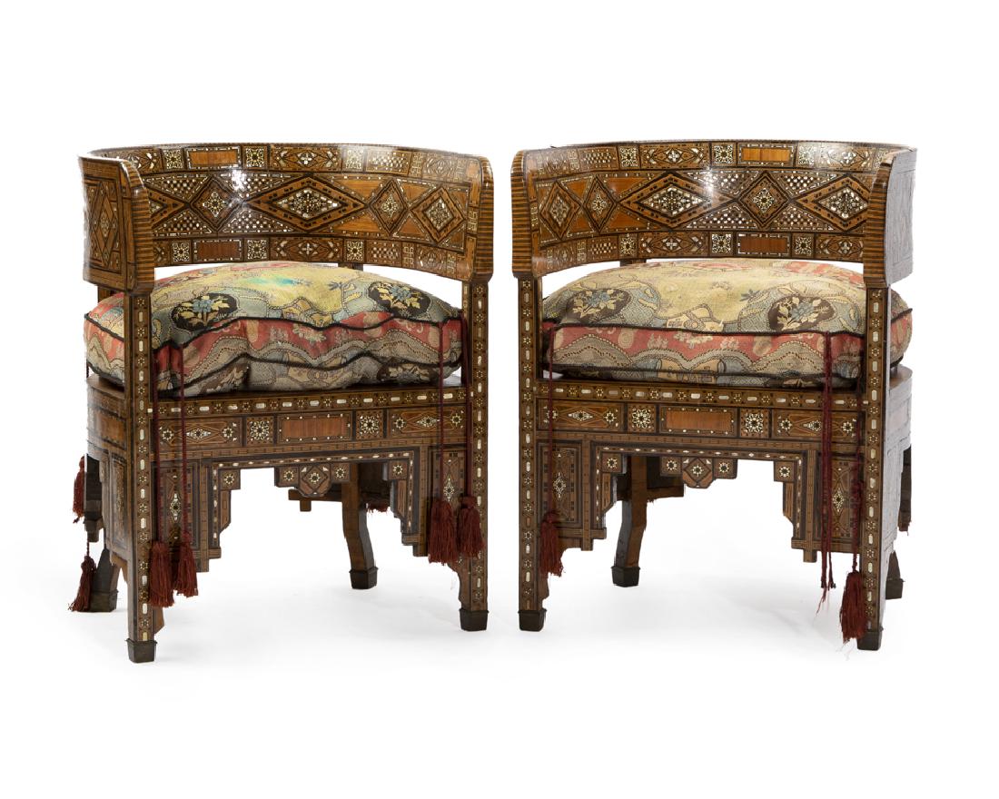 A pair of Syrian parquetry barrel chairs: Second half of 19th century Inlaid with mother-of-pearl, bone, and various fruitwoods with rounded back enclosing a conforming seat with upholstered drop-in cushion, the slender squared legs connected
