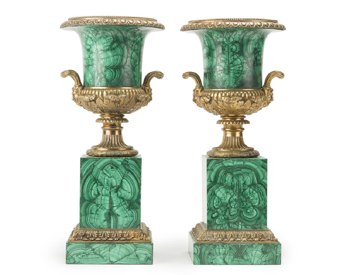 A pair of malachite-veneered urns: Second half 20th century Comprising two gilt bronze-mounted malachite-veneered urns flanked by pan-mask handles over a stepped square plinth, 2 pieces Each: 18.5" H x 8" W x 6.5" D