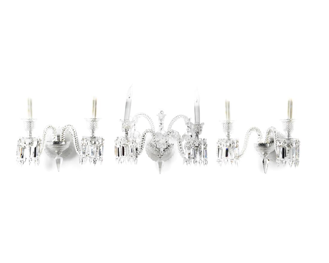 Three Baccarat wall sconces: Late 20/ early 21st century Signed: Baccarat Each two-light sconce with cut-crystal supports issuing twisted arms holding cut-crystal bobeches with crystal drapes, comprising one large and two small s