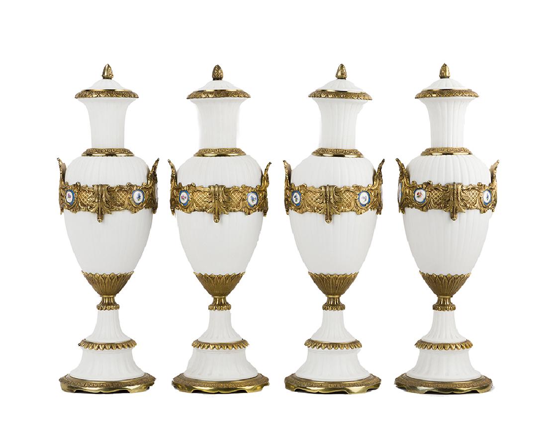 Four gilt-bronze and bisque urns: 20th century Each ridged white bisque vase set with gilt-bronze mounts and inset Sevres-style plaques, 4 pieces Each: 24" H x 7" Dia.