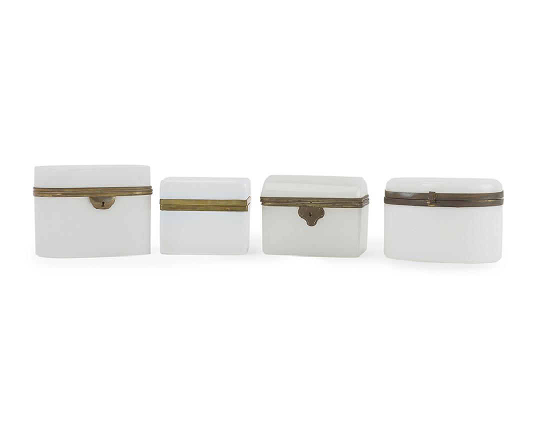 Four opaline glass vanity boxes: 20th century Each white opaline box set with metal mounts comprising one rectangular, one oblong, one oval box, and one round-top trunk-shaped box, 4 pieces Largest: 4.25" H x 5.625" W x 3.75" D