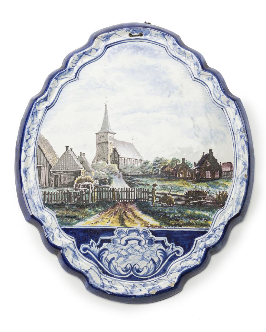 A hand-painted Delft-style pottery wall plaque: Fourth quarter 19th century, Danish Signed verso: FJ Polychrome with scalloped blue edge depicting bucolic village with a boy looking disappointedly at a cart full of hay, lower portion with a painted