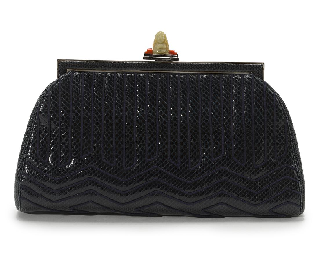 A Judith Leiber snakeskin clutch: Jade Buddha and coral clasp, silver-tone hardware, chevron cord overlay to exterior, dark blue satin interior, optional chain-link shoulder strap 6.5" H x 9.75" W x 1.5" D