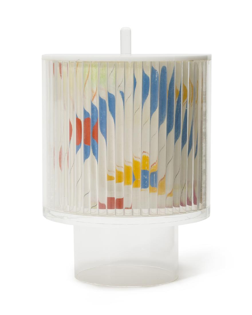 Color whirligig by M. Kirkpatrick: 1981 Signed, titled and dated to paper interior: M. Kirkpatrick, 1981 with copyright symbol The clear acrylic centrifugal body, foot, and finial with white acrylic top enclosing a body with rows of ro