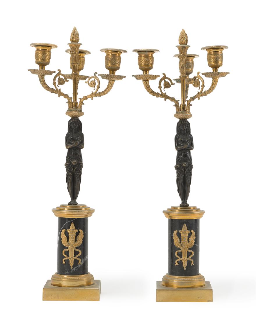 A pair of Italian Egyptian revival candelabras: Second quarter 20th century Metal tag to branch: Made in Italy The three-light candelabra with central Egyptian female shaft over a black marble pillar with applied torch chalice 18.5" H x 7" W x 7" D