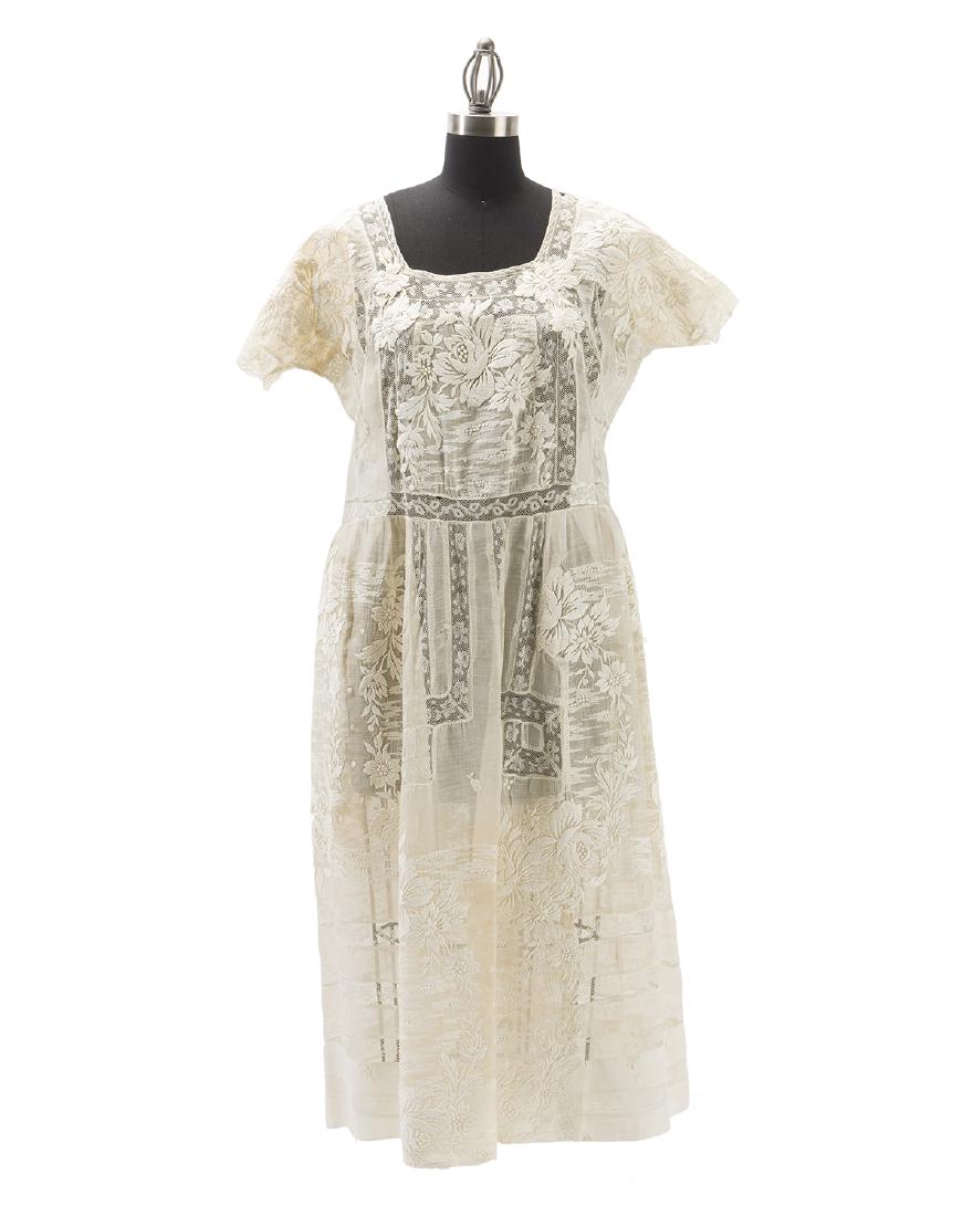A ladies dress: First quarter 20th century The embroidered linen dress designed with a squared neckline, cap sleeves, and machine lace panels with button and replaced snap closures Neck seam to hem: 43" H; Cuff to cu